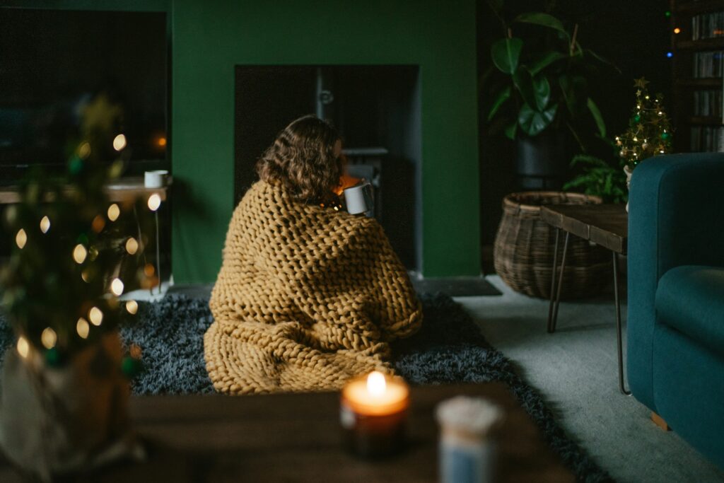 Woman cuddled in a blanket, sipping a warm beverage and relaxing