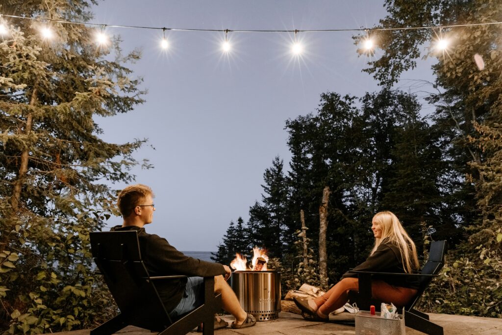 A man and a woman catching up while relaxing at a camp fire