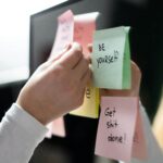 Person sticking sticky notes about improving yourself