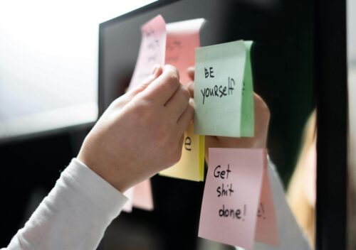 Person sticking sticky notes about improving yourself