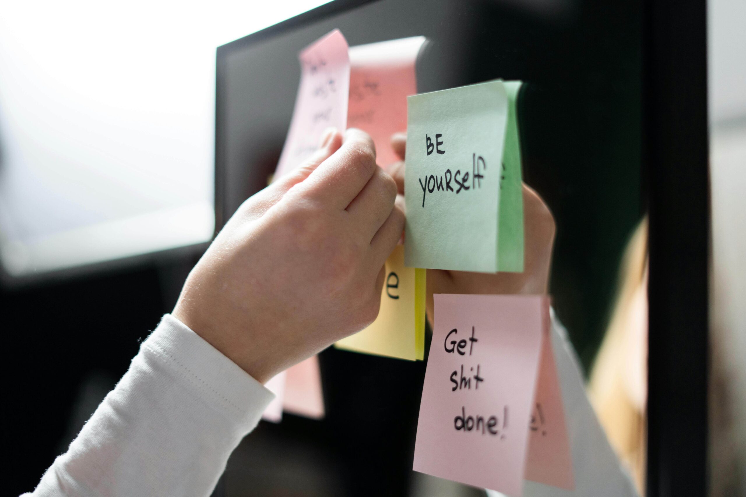 Person sticking sticky notes about improving yourself