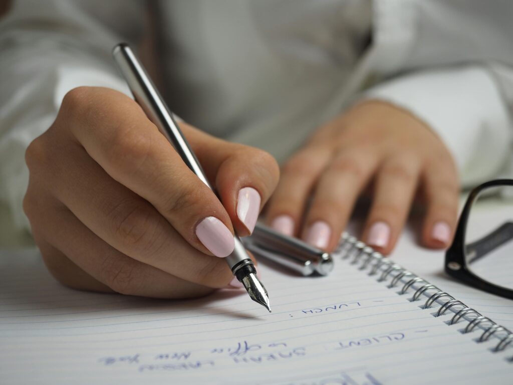 A lady journalling what she is looking forward to and answering her Christmas journal prompt