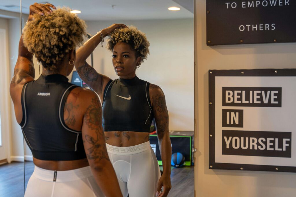 Lady looking at herself in the mirror with a self-improvement quote hanging on the wall